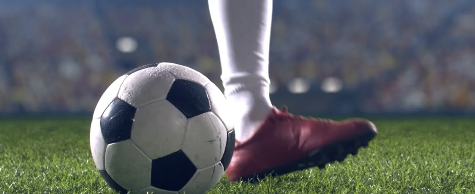 Soccer ball on pitch with player kicking ball